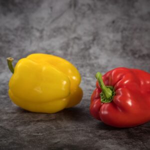 Close-up of fresh red and yellow bell peppers on a gray surface. Perfect for healthy food concepts.
